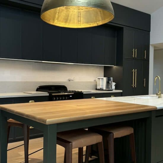 Racing-green shaker kitchen with brass hardware and a solid timber island top