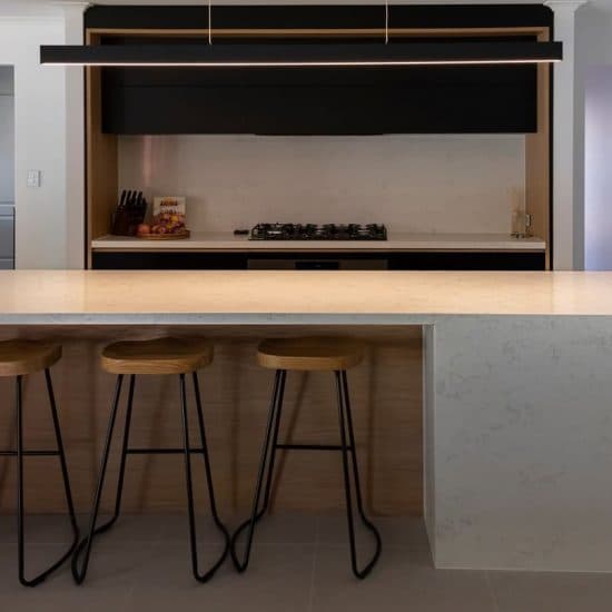 Black cabinetry kitchen with a floating timber-lined cooking nook and marble waterfall island