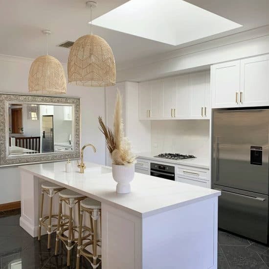 Bright white shaker kitchen with rattan pendants and a skylight over the island