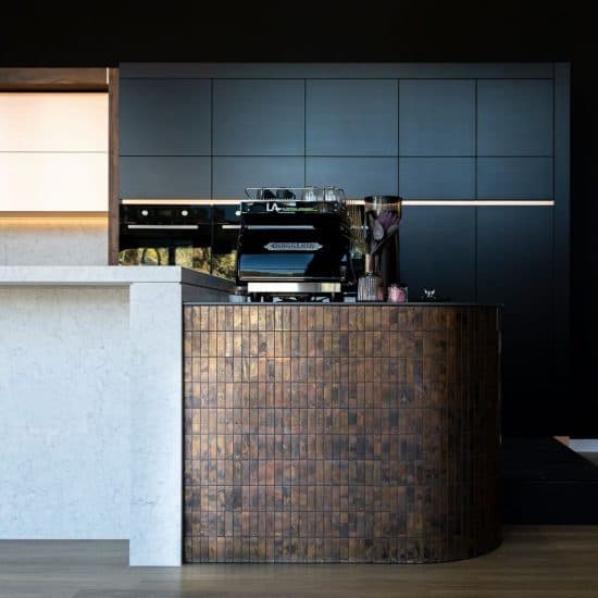 Navy cabinetry kitchen with a hand-tiled copper-tone island base and integrated coffee station