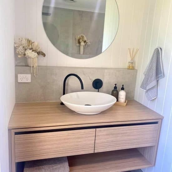 Timber vanity with a round mirror and matte-black tapware