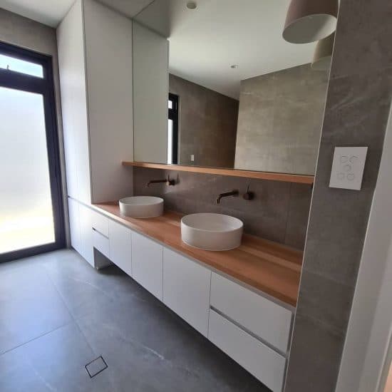 Double floating vanity in a light-filled ensuite with a full mirror wall