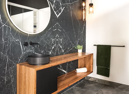 Black marble ensuite with a floating oak vanity and matte-black tapware